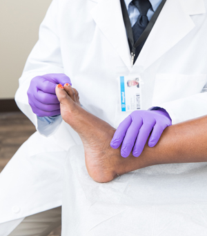 Gros plan d'un professionnel de la santé examinant le pied d'un homme.