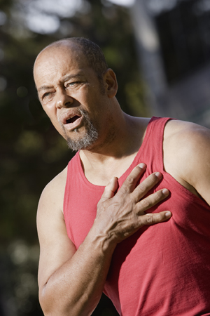 Homme saisissant sa poitrine de douleur.