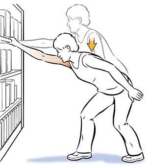 Mujer que hace un ejercicio de elevación del hombro, sosteniéndose de una biblioteca.